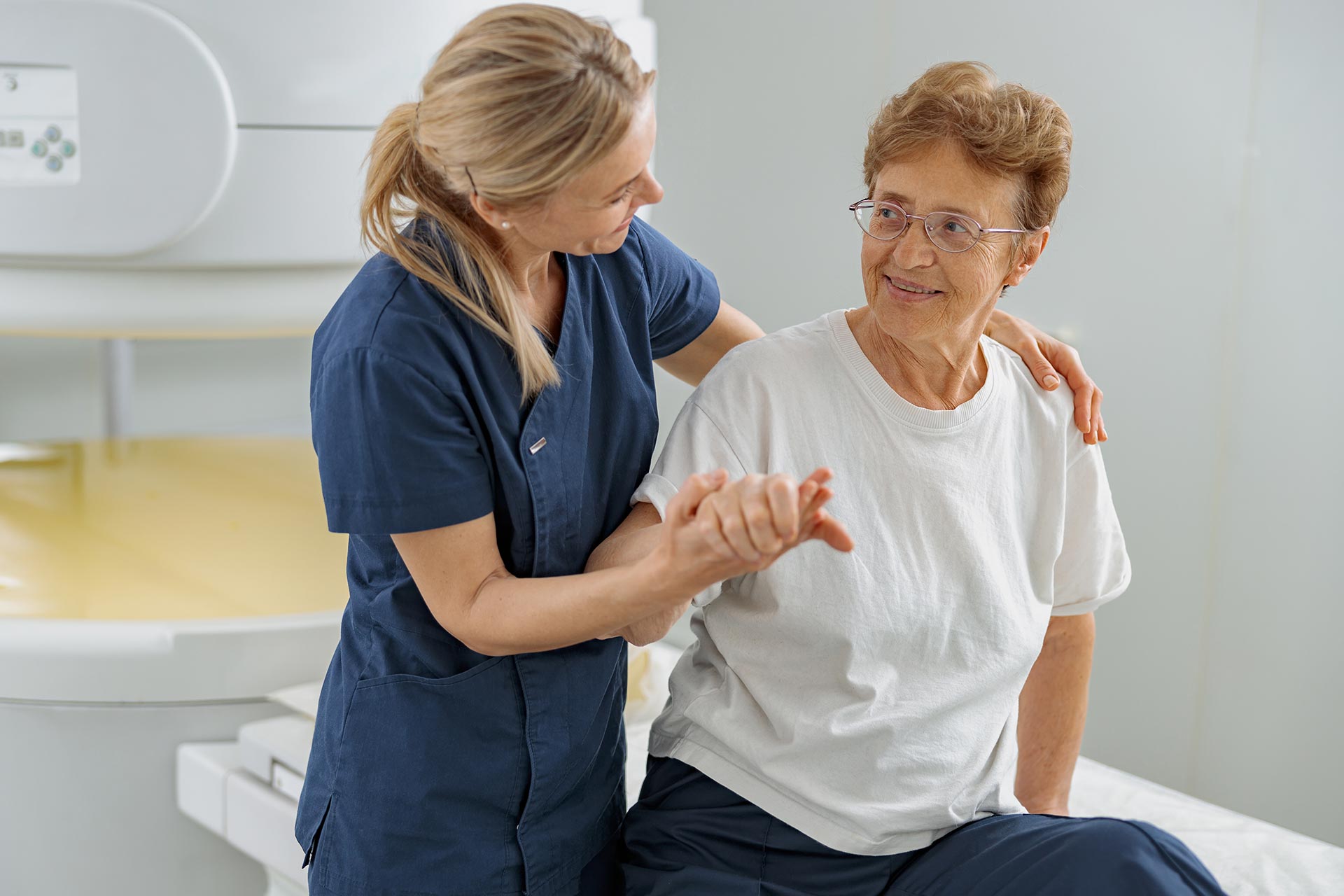 A therapist holding the hand of an elderly woman.